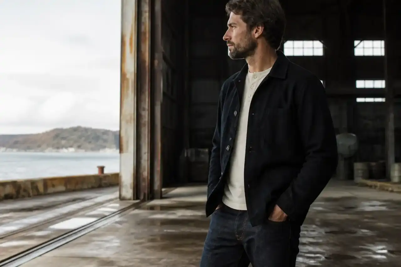 Intérieur d'un hangar maritime avec des vêtements de travail suspendus et des outils anciens
