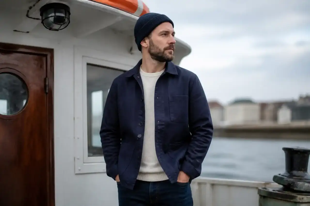 Mannequin portant une veste de docker brute devant un hangar industriel rénové